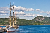 The barque 'Picton Castle' moored at the old fishing wharf amidst forests and mountains.