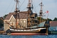 Image of Replica pirate ship 'Hector' moored to the Pictou wharf, alongside colonial style buildings.