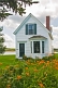 Traditional white washed weatherboard house with garden of orange flowers.