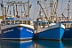 Image of Three blue fishing boats moored to the wharf.