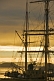 Image of Masts and rigging of the barque 'Picton Castle' against a cloudy sky at dawn.