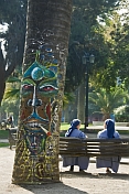 Two nuns sit next to graffiti-covered tree.