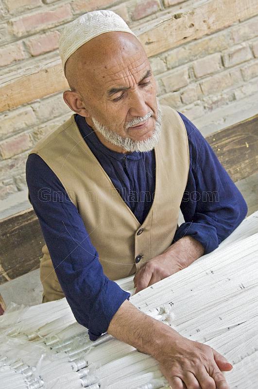 Elderly Uighur man preparing silk for tie-dying.