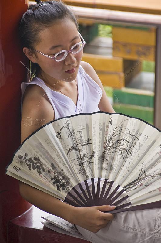 Chinese girl with white paper fan in Jingshan Park.