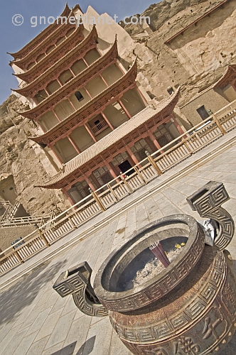Incense burns in front of the multi-layered roofs that protect access to the Buddhist Mogao Caves.