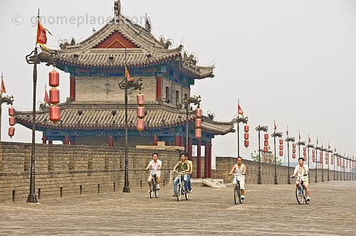 Chinese men ride bicycles along the city walls.