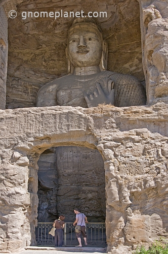 Two western tourists looking at a giant Buddha statue at the Yungang Buddhist caves, near Datong.