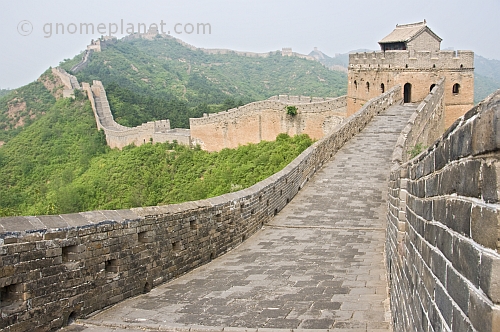 The Great Wall of China crossing forested mountain ranges.