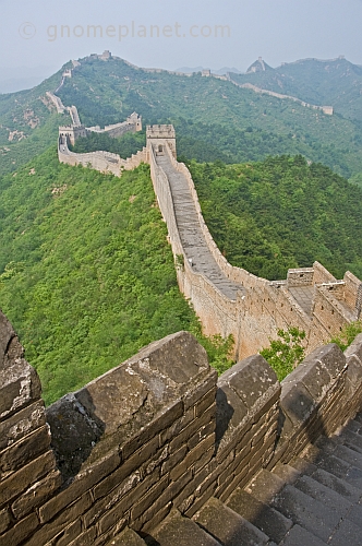 The Great Wall of China crossing forested hills and mountains.
