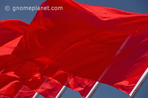 Red Chinese flags billowing in the wind of Tiananmen Square.