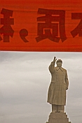 Statue of Chairman Mao Tsedong under red banner with Chinese characters.