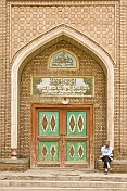 Muslim man sitting next to the entrance door to a mosque.