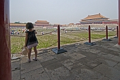 A small Chinese girl watches tourists in the Forbidden City.