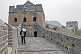 Image of A male worker cleans weeds from the Great Wall of China.