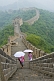 Two Chinese ladies with umbrellas walk along the Great Wall of China.