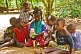 Image of Group of children sit in the shade and play with a plastic doll.