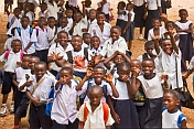 Smiling schoolchildren in white shirts enjoy having their photograph taken.