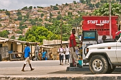 Boy walking on a service station forecourt whilst the attendant sells petrol.