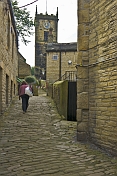 Woman walks up cobbled backstreet towards Holy Trinity Church in Towngate.
