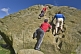 Climbers in red and blue shirts climb the Cow and Calf Rocks on Ilkley Moor.