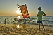 caption: Boy watches 'Oruwa' outrigger fishing boat